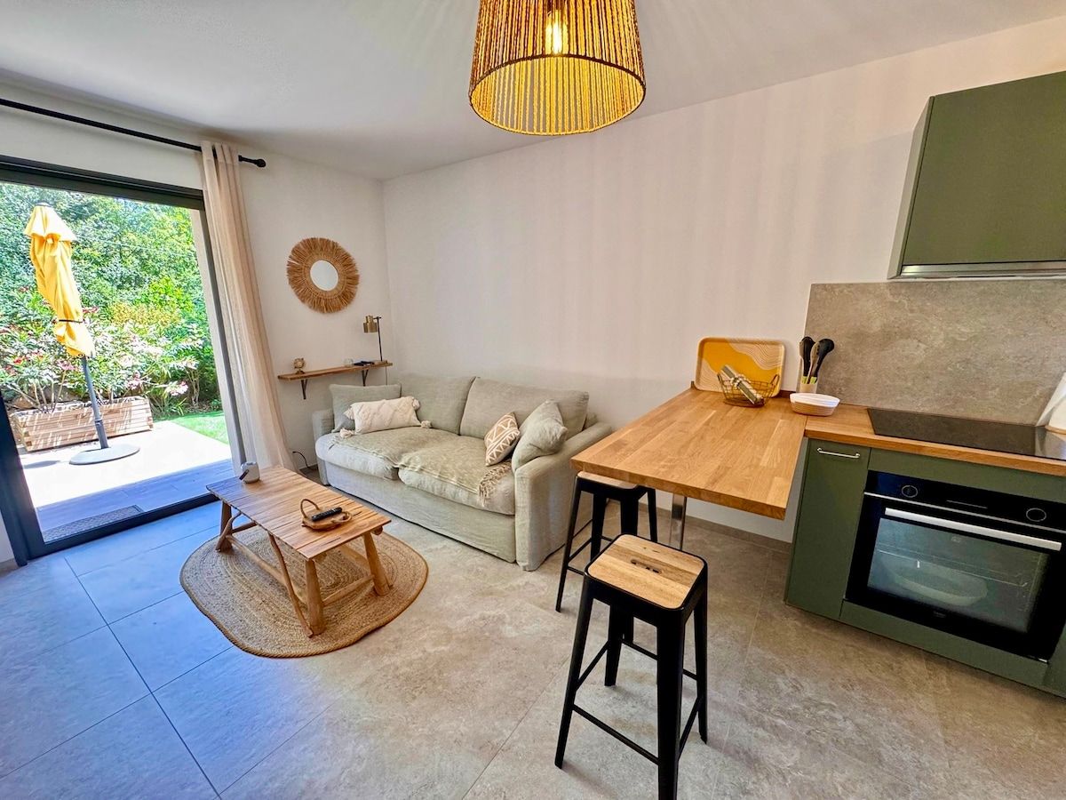 Bright living room with sofa, wooden high table and sage-green kitchen