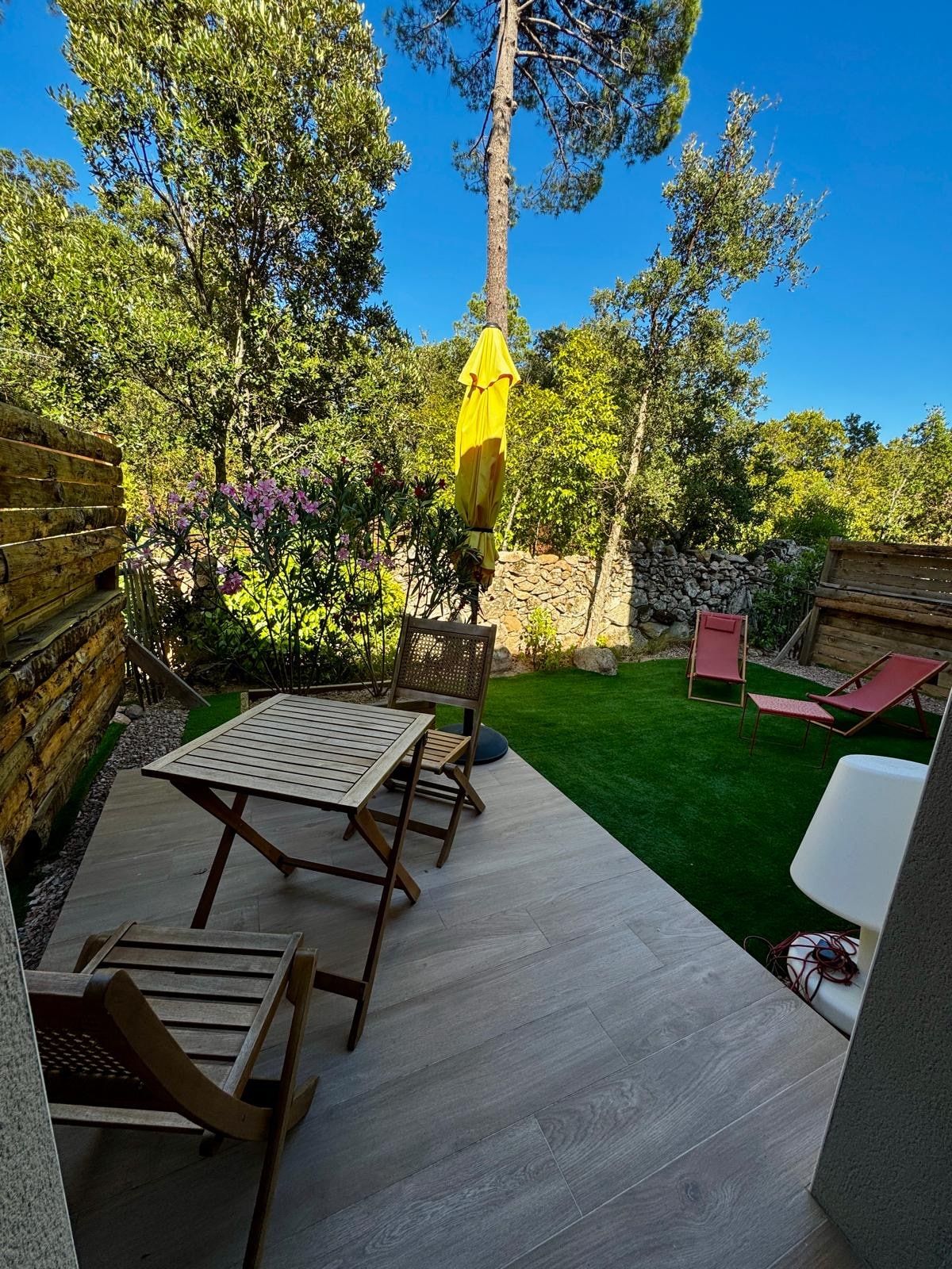 Terrasse dallée avec table, parasol et jardin arboré