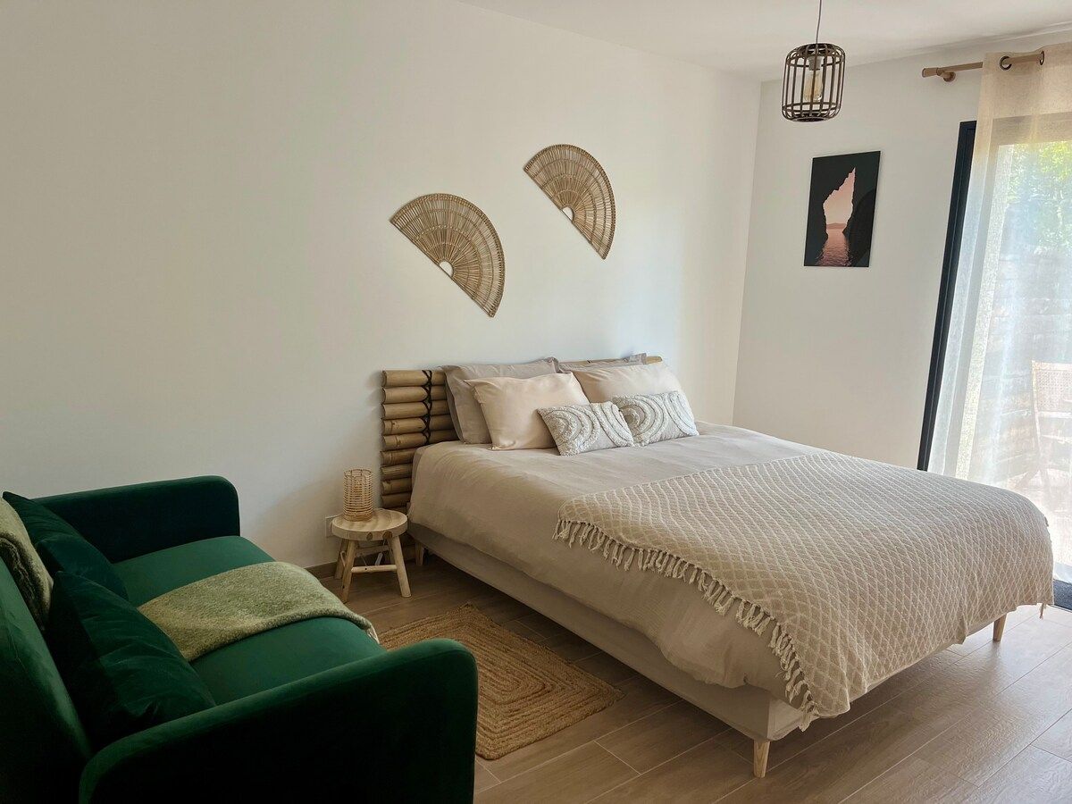 Vue d’ensemble de la chambre avec son canapé vert et son grand lit