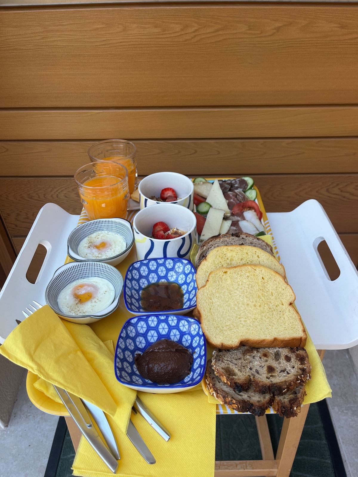 Plateau de petit-déjeuner avec œufs, jus de fruits, yaourts et pains maison
