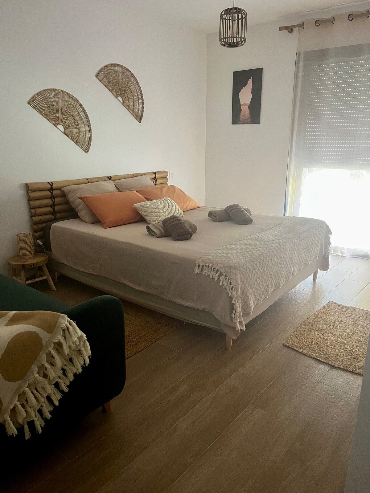 Bed dressed with terracotta cushions, green sofa and natural-fibre decor