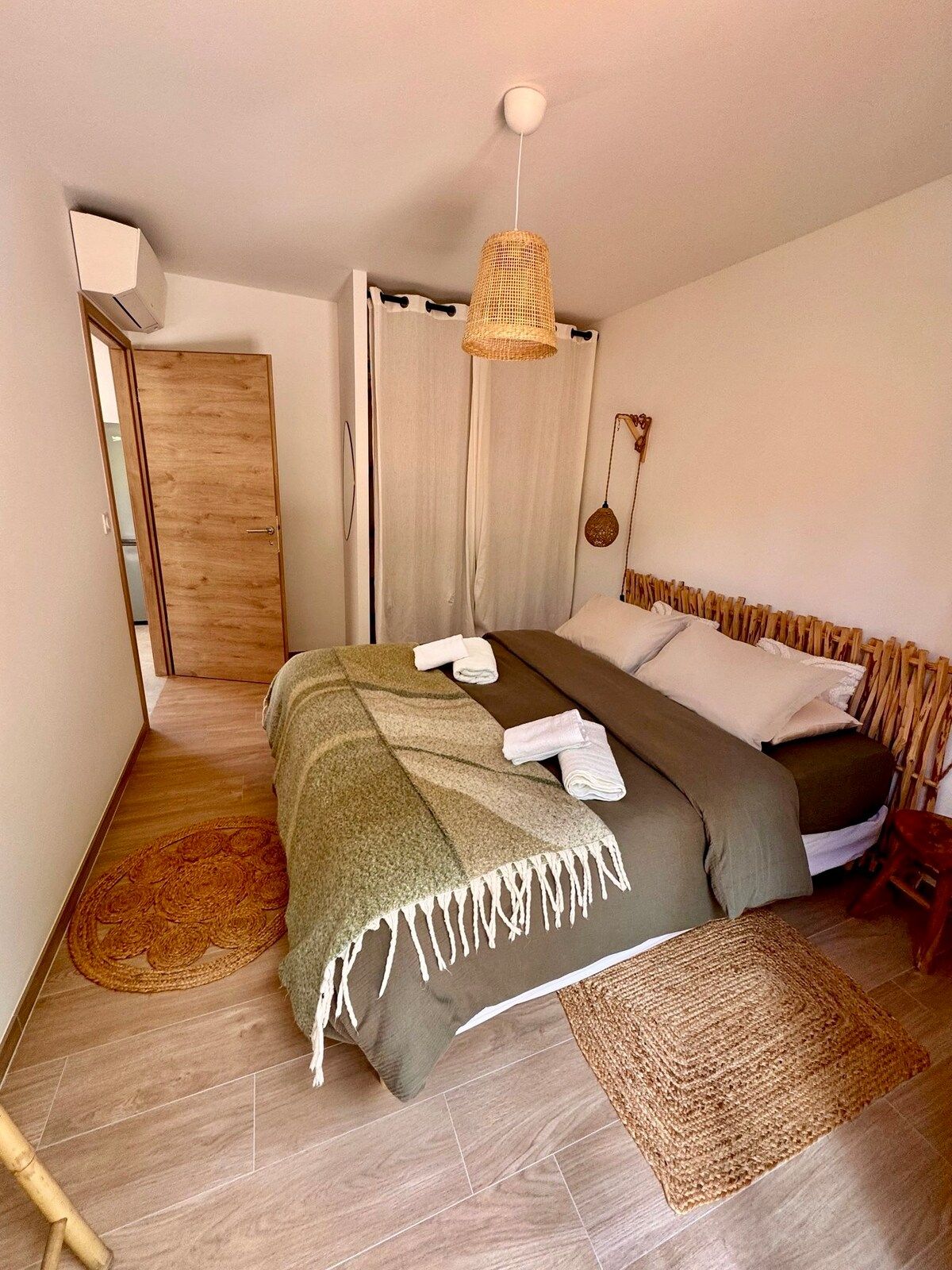 Bedroom seen from the doorway, bed dressed in natural linen