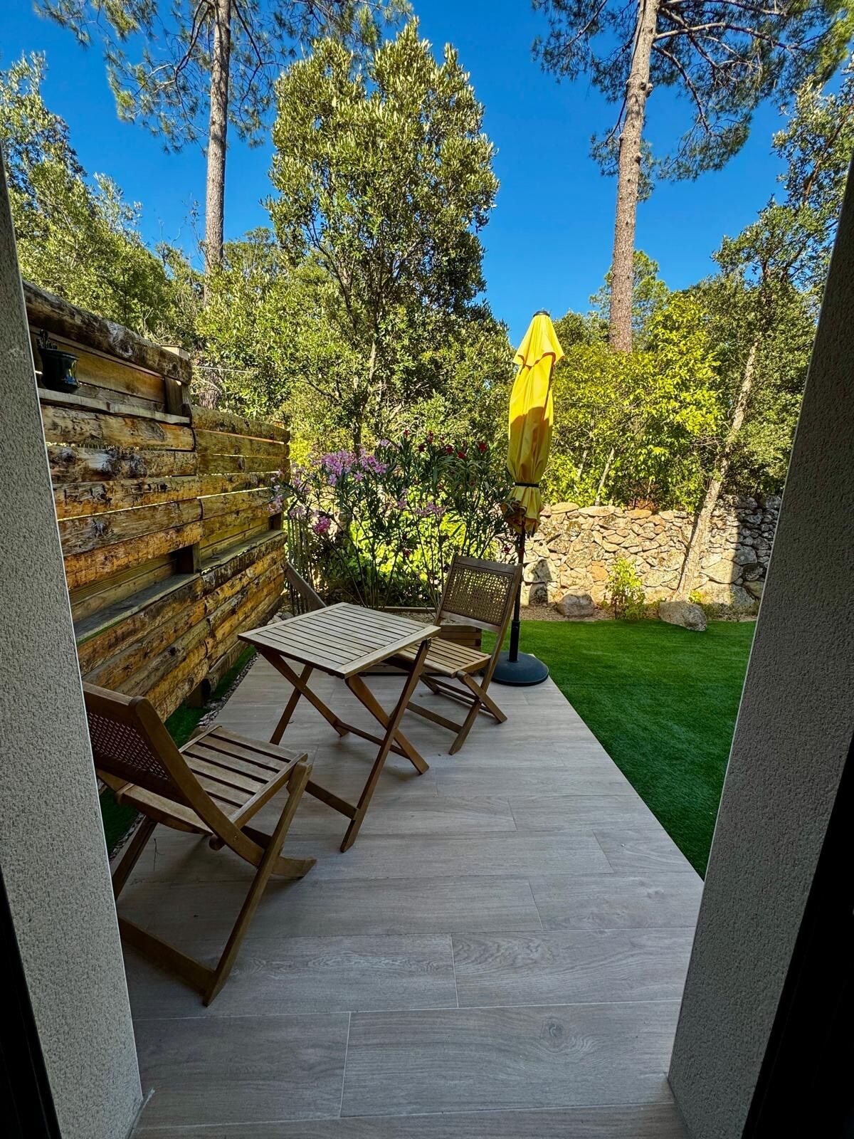 Terrasse avec mobilier de jardin et parasol jaune, sous un ciel bleu