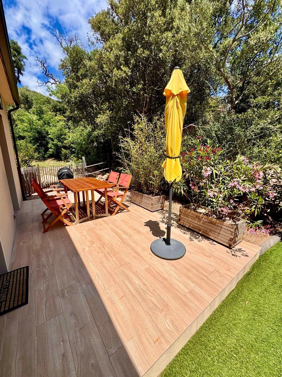 Light wooden terrace with table, parasol and lawn